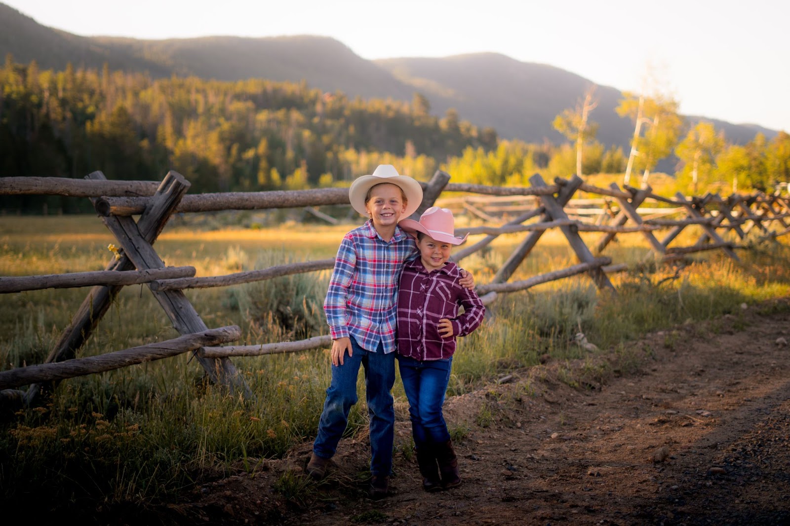 Photo of two kids smiling with mountain landscape during a family ranch vacation at Rawah