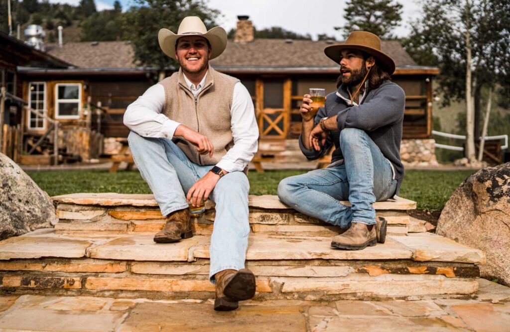 Two men sitting on the steps at Rawah Ranch during a Colorado summer vacation